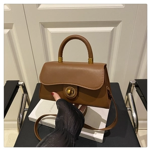 Detailed macro view of retro brown crossbody bag with unique golden circular twist lock