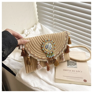 Detailed close-up of woven straw handbag featuring colorful embroidery and tassel charms