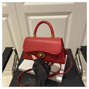 Detailed view of red leather crossbody bag with vintage gold hardware and wavy flap