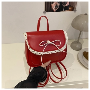 Dettaglio mini zaino in pelle PU rossa con bordo in pizzo bianco e decorazione a fiocco