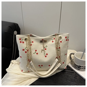 Detail der cremefarbenen Cord-Tote-Bag mit Kirschmuster, Goldkette und Hirsch-Anhänger