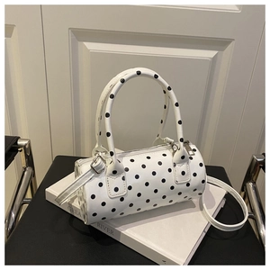 Detail of a white barrel bag with black polka dots featuring silver zipper and dual handles