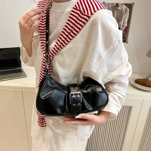Chic black patent leather crescent shoulder bag with silver buckle and eyelet strap