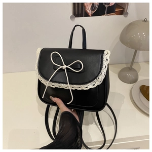 Dettaglio mini zaino nero in pelle con bordo in pizzo bianco e decorazione fiocco