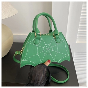 Detail of green bat-shaped handbag with white spider web stitching and golden hardware