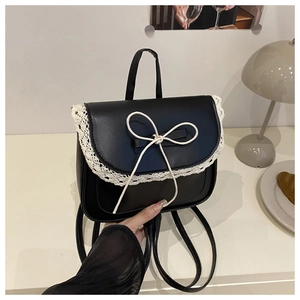 Dettaglio mini zaino in pelle nera con bordo in pizzo bianco e decorazione a fiocco