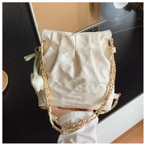 Detail of white quilted leather chain bag with floral pendant and gold chain strap