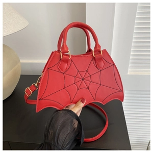 Detail of red bat-shaped handbag featuring black spiderweb stitching and gold hardware