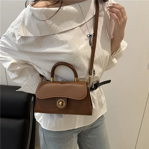 Brown vintage leather crossbody handbag with round metal lock shown on a female model