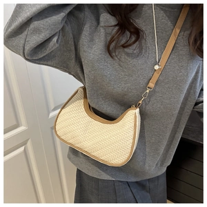 Detail of woven crescent bag with brown leather trim and metallic gold buckles on a model