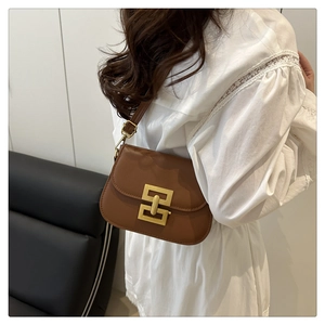 Braune Retro-Satteltasche aus Leder mit goldenem Verschluss am Model für trendigen Look