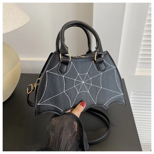 Detail of bat-wing shaped handbag featuring white spider web embroidery and gold hardware
