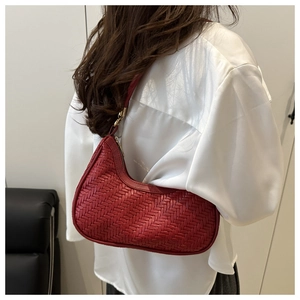 Detail of red woven crescent shoulder bag featuring intricate texture and golden hardware