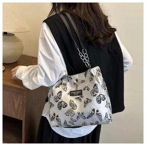 Détail du sac à bandoulière argenté avec broderie papillon et bandoulière en chaîne