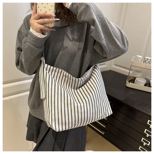 Close-up of black and white striped canvas tote bag with wide shoulder strap details