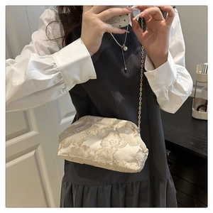 Close-up of champagne gold floral jacquard chain bag with elegant textured fabric details
