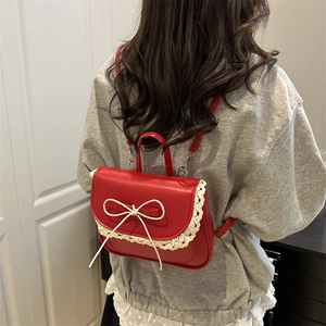 Mini zaino rosso con bordo in pizzo bianco e fiocco, indossato da una modella nel dettaglio