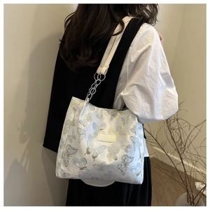 Détail de la broderie papillon et du logo en cuir sur le sac cabas blanc pour femme