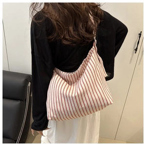 Close-up of a large striped canvas tote bag showing red vertical lines and wide strap