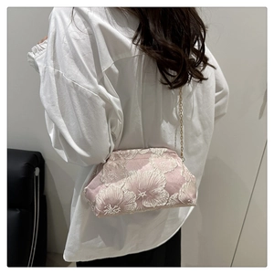 Detail of pink floral lace embroidery on satin crossbody bag with gold chain strap