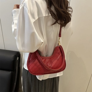 Stylish red woven crescent bag in a half-moon shape shown from a 45-degree angle