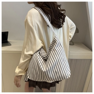 Detailed back view of a large black and white striped canvas tote bag worn on shoulder