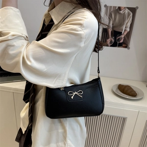 Classic black baguette shoulder bag featuring a golden bow buckle and lychee leather texture