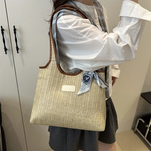 Straw tote bag with brown leather trim and blue scarf shown on model shoulder