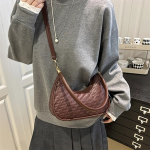 Deep brown woven crescent bag with adjustable shoulder strap and gold hardware on model