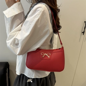 Red underarm baguette bag with lychee texture and gold bow detail for stylish women