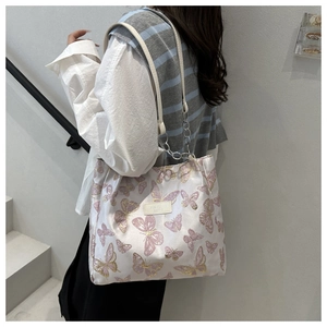 Détail de la broderie papillon rose et de la bandoulière chaîne sur le sac beige