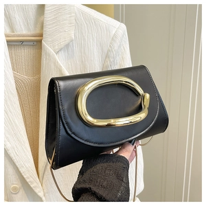 Détail du sac à bandoulière en cuir noir avec grande poignée sculpturale dorée