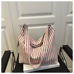 Detail of red and white striped canvas tote bag with wide straps on a black chair