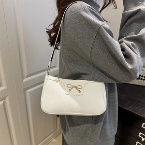 White faux leather baguette shoulder bag with gold bow and flower pendant detail