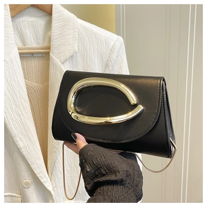 Détail du sac bandoulière noir minimaliste avec poignée en métal doré en forme de C