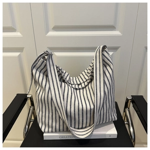 Close-up of blue and white striped canvas tote bag on a black chair in a minimalist room