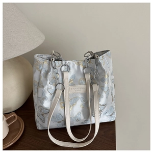 Détail d'un sac cabas à motif papillon avec bandoulière chaîne et étiquette en cuir