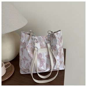 Détail des motifs papillons brodés rose et or et de la chaîne argentée sur le sac