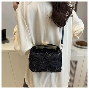 Détail de fleurs en mesh 3D et boucle en métal doré sur un sac seau à bandoulière noir