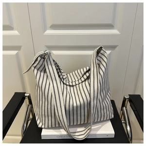 Detail of adjustable metal buckle and striped canvas fabric on a large tote bag