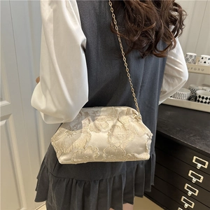 Elegant off-white floral embroidered shell bag with gold chain strap on model