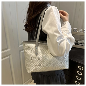 Detail of white tote bag with gray geometric patterns and metal rivets on shoulder straps