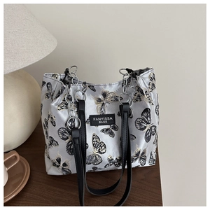 Détail du sac bandoulière en soie argentée avec broderies papillon et chaîne noire