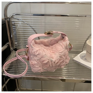 Détail de pétales de rose 3D sur sac de soirée rose avec fermoir doré et bandoulière