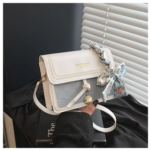 Detail of square crossbody bag with blue silk scarf handle and leather text branding