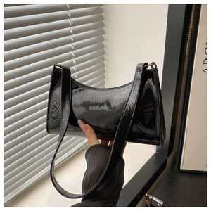 Close-up of black patent leather baguette bag with high-gloss finish and light shadows
