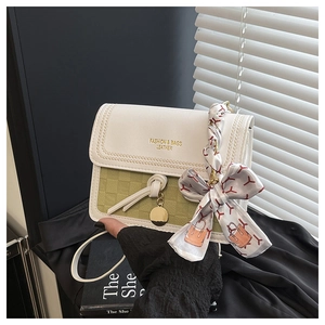 Close-up of green woven texture bag featuring a silk scarf bow and gold logo detail