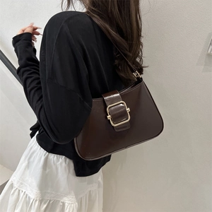 Deep brown faux leather baguette shoulder bag with gold buckle on a female model