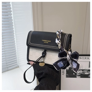 Detail of contrast crossbody bag featuring woven texture and scarf-wrapped chain handle