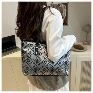 Detail of silver tote bag with floral embroidery and black straps for daily commute